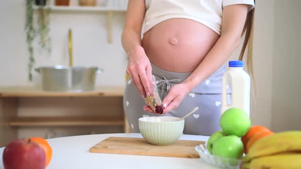 Pregnant Mom Prepare Cereal Pour Oatmeal Muesli in Plate in Kitchen Close Up Spbd