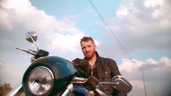 Young Man Sitting on Motorcycle on the Road at Sunset Slow Motion