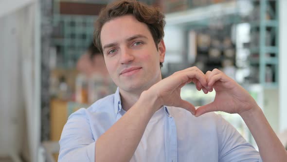 Portrait of Young Man Showing Heart Sign By Hand