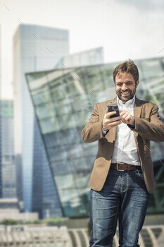 Businessman using smartphone touchscreen in city