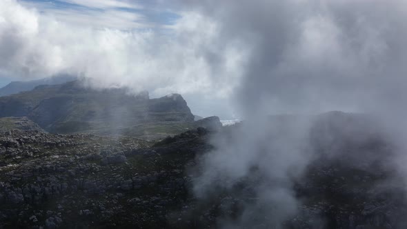 Dense white fluffy clouds above mountain range in South Africa, aerial view