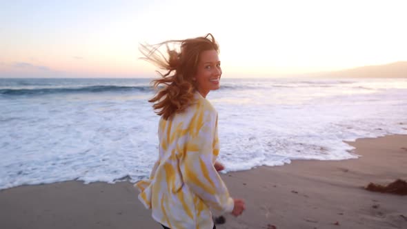 Happy and playful woman at the beach at sunset