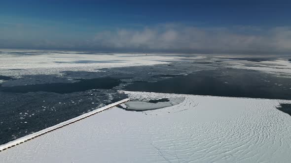 Aerial drone view of ice chunks and frozen pier in Michiagn in winter