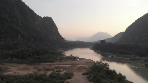 Aerial: drone flying over Nam Ou River valley canyon Nong Khiaw Muang Ngoi Laos, sunset dramatic sky