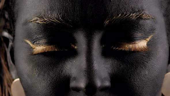 Closeup of a Young Beautiful Woman's Face with Black and Gold Paint on Her Skin