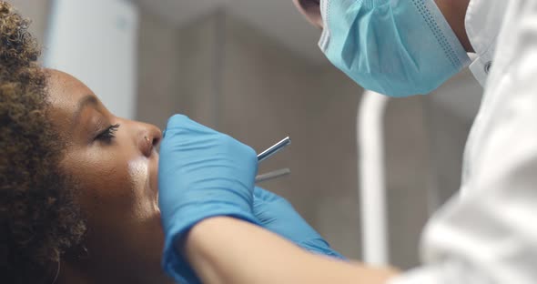 Close Up of Dentist Examining Female Patient Mouth in Dental Clinic