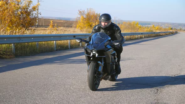 Young Man Riding on Modern Sport Motorbike at Autumn Highway