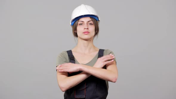 Portrait of Caucasian Young Woman Worker in Jumpsuit Putting on Helmet During Work on Factory or