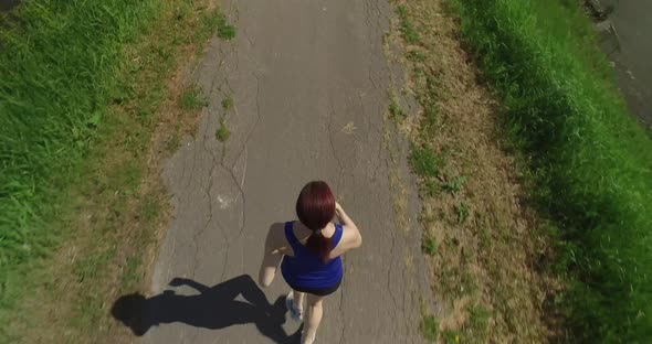 A unique top down view of a woman as she goes for a jog on a sunny day.