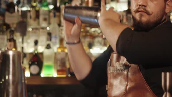 Stylish Adult Barman Is Shaking Cocktail in a Shaker Standing Behind the Bar