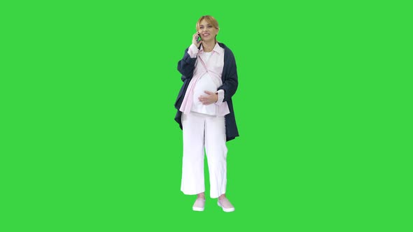 Attractive Pregnant Woman Making Phone Call and Holding Her Tummy on a Green Screen Chroma Key