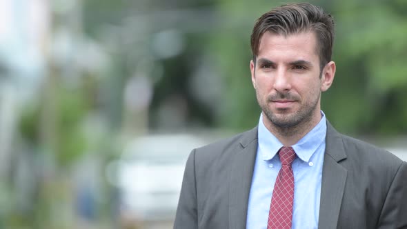 Young Happy Hispanic Businessman Thinking Outdoors