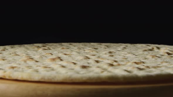 A Pizza Dough Is Rotating On A Black Background