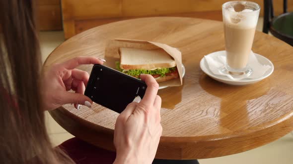 Trendy Woman Wearing Red Dress in a Cafe Make Photo of Sandwich Food with Mobile Phone Camera