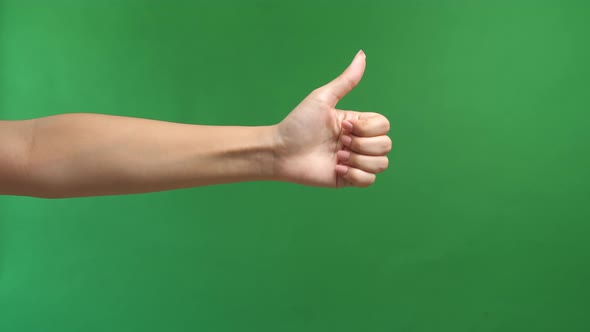 Closeup Of Female Hand Showing Thumbs Up Sign Against Green Screen Background