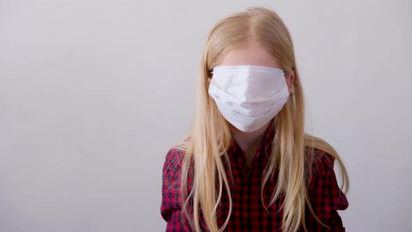 Blonde Girl Putting on Wearing Surgical Medical Face Mask Against Infectious Disease Protection