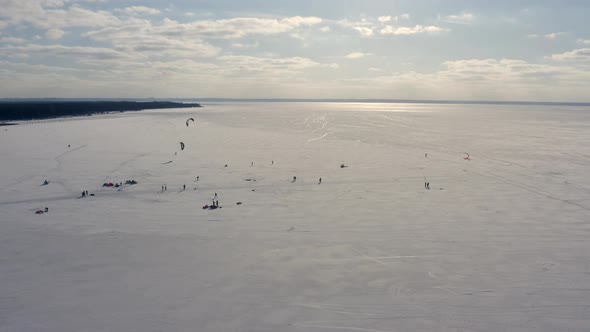 A Group of People on a Frozen Winter River are Preparing for Snow Kiting