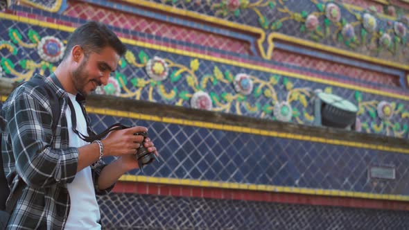 Young asian man tourists walking traveling with nose ring taking photo on camera of temple thailand