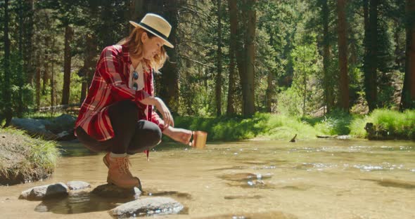 Slow Motion Young Woman Sitting at the Forest River and Drinking Clear Water, 