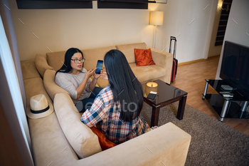 Mother scolding daughter for viewing inappropriate content on smartphone in suite