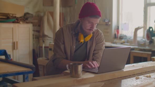 Woodworker Browsing the Web on Laptop in Workshop