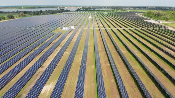 Aerial View of Solar Power Station. Panels Stand in a Row on Green Field. Summer