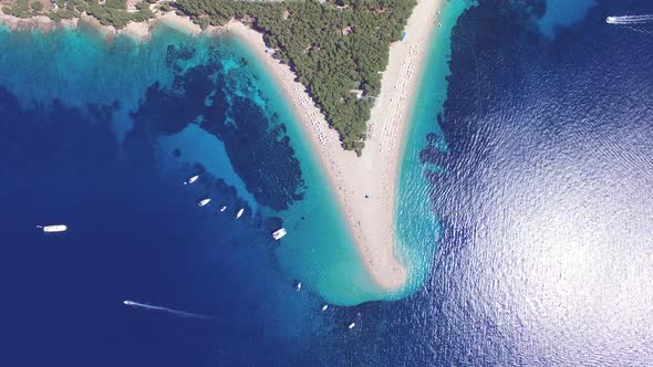 Motorboat passing the sandy beach Zlatni rat on the island of Brac, Croatia