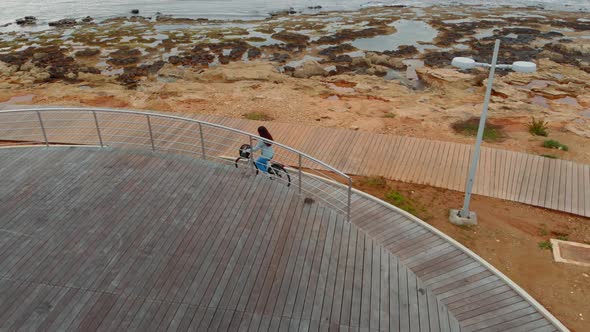 Female Cyclist Cycling Along the Sea Coast, Air Shot, Sports Lifestyle Inspirational Concept