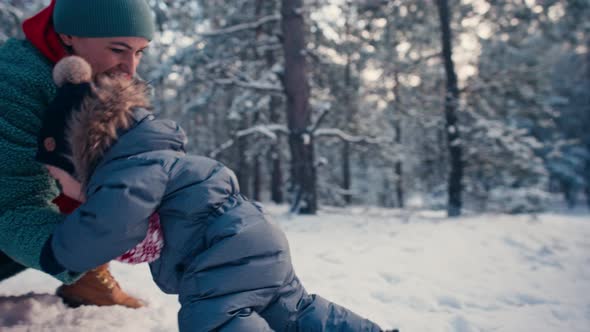 Mother Learning Her Little Baby Son His First Steps in the Snow Forest