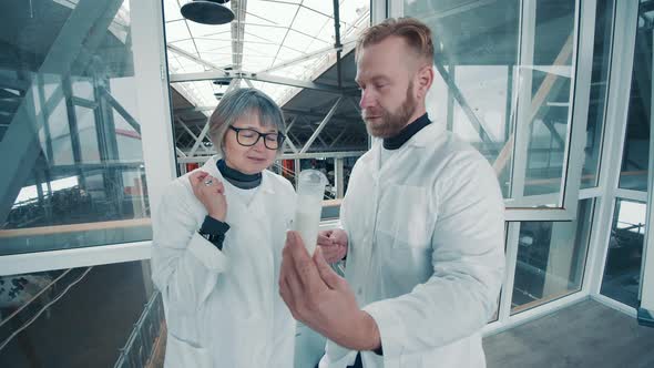 Two Farm Experts are Discussing a Milk Sample in a Tube