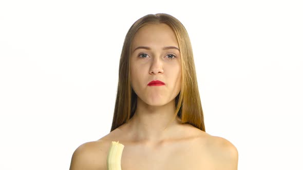 Girl with Braces and Red Lips Eating a Banana and Looking at the Camera, White, Closeup