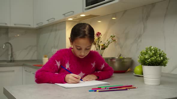 Adorable Girl in Pink Pullover Drawing Picture in Sketchbook at Home