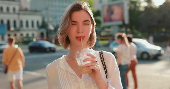 Happy Woman Drinking Cold Latte in a City