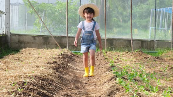 Little girl wearing a hat helps her mother in the garden, a little gardener.