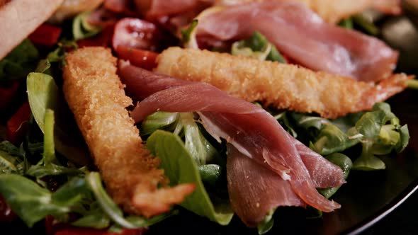 Salad with fried shrimps, parma ham and cherry tomatoes, close up