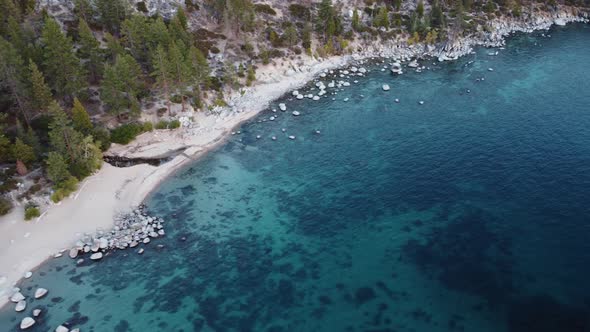 Drone shot of Chimney Beach and the crystal clear blue water of Lake Tahoe during sunset. This color