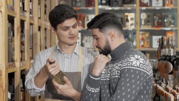 Male Shop Assistant Helping His Male Customer Choosing Alcohol to Buy