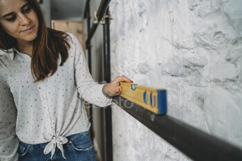 Woman checking the level of a shelf with a spirit level