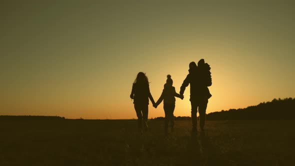 Happy Young Family Together with Children at Sunset. People Silhouettes on Summer Sunset Meadow