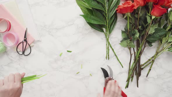 Time lapse. Flat lay. Florist pruning red roses for bouquet arrangement.