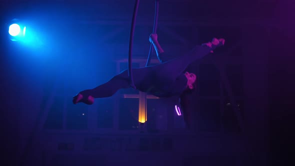 Silhouette Aerial Gymnast Performs Trick in Ring in Smoky Room with Backlit