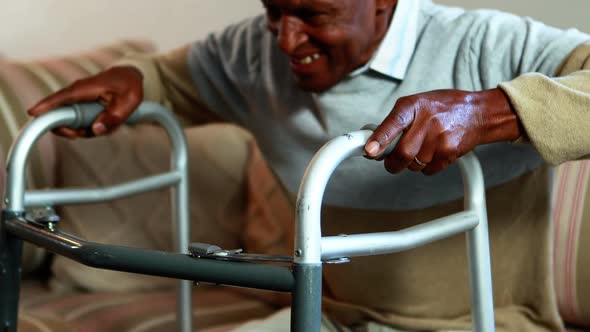 Senior man getting up from sofa with walker