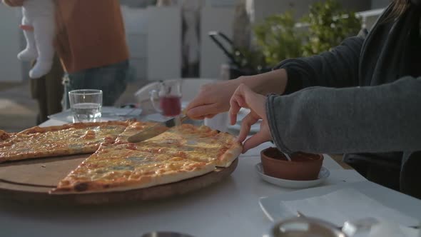 Female hand cuts pizza in a cafe. Meeting friends in a restaurant