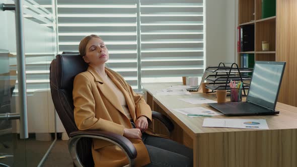 Tired business woman lying on chair and closing her eyes after hard working day.