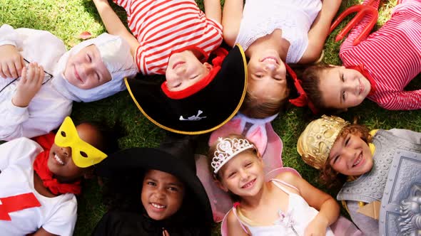Group of kids in various costumes lying on grass alt
