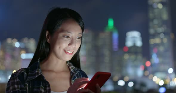 Woman use of mobile phone in city at night