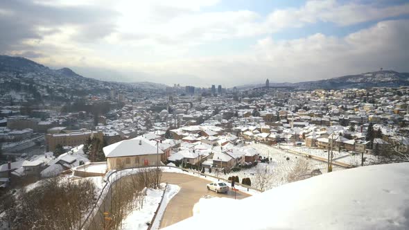 Overview of a road and the snow-filled rooftops of a neighborhood in Sarajevo