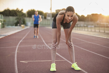 Female athlete resting after a sprint on the track at sunset