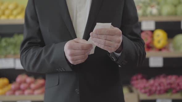 Front View of Unrecognizable Caucasian Man Holding Bill in Hands and Checking Price of Purchased