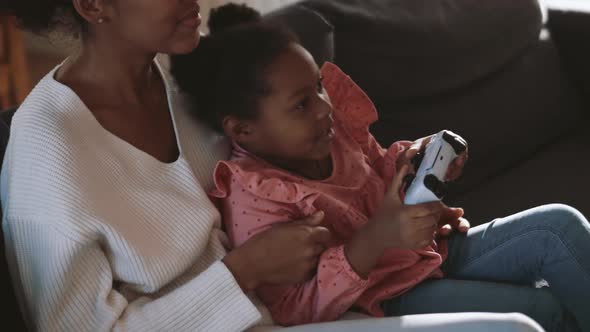 Positive girl playing game with gamepad with mother